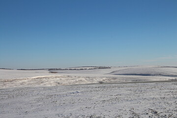 Fototapeta na wymiar A snowy landscape with a blue sky
