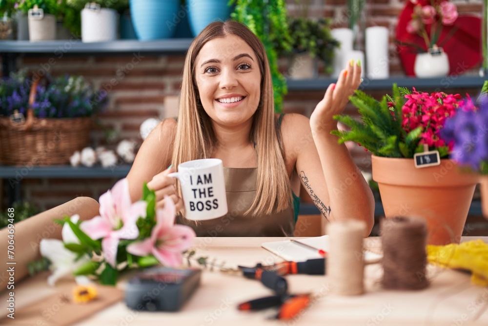 Poster Young blonde woman working at florist shop holding i am the boss cup celebrating achievement with happy smile and winner expression with raised hand