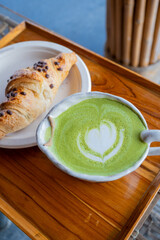 Close-up photo of green tea latte art paired with croissants