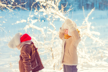 Children play in a winter snowy forest.