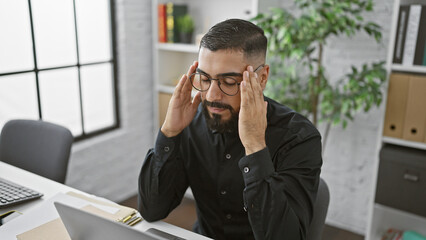 Stressed businessman at office rubbing temples