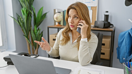 Hispanic businesswoman on a phone call looking perplexed in a modern office setting