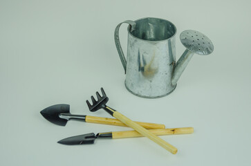 garden tools, rake and shovel next to a watering can on a light background,