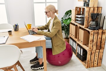 Young blonde woman business worker using laptop sitting on fit ball at office