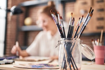 Young blonde woman smiling confident drawing on notebook at art studio
