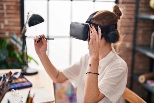 Young blonde woman using virtual reality glasses drawing at art studio