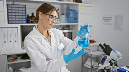 Attractive young hispanic female scientist measuring liquid in a test tube, engrossed in her...