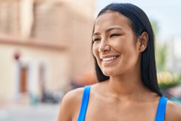 Young beautiful latin woman smiling confident looking to the side at street
