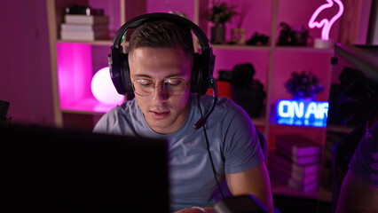 A focused young man gaming at night in a vibrant home room adorned with neon lights.