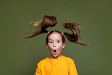 Photo of astonished little schoolgirl with fluttering ponytails wear yellow pullover staring open...