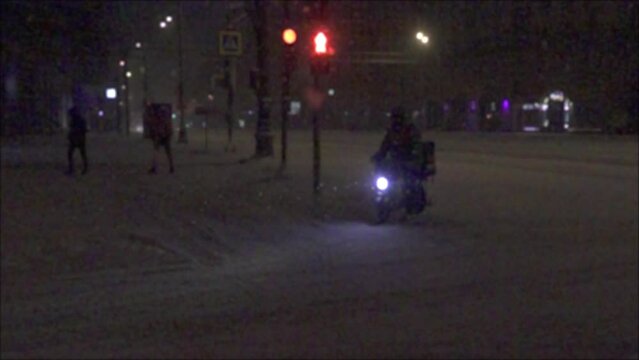 Heavy snowfall overnight (weather disturbance), has been hammered with snow. City transport drives on a snow-covered road. Super slow motion 1000 fps. Blurred, unrecognizable person.