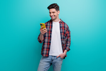 Photo of positive funky man dressed plaid shirt chatting modern device isolated turquoise blue...