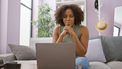 African american woman using laptop at home on a couch