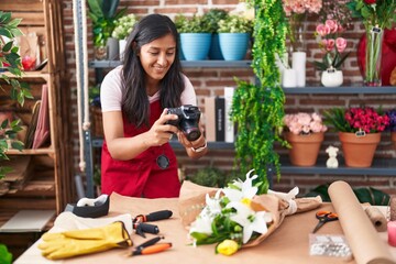 Young beautiful hispanic woman florist make photo to bouquet of flowes gift at flower shop