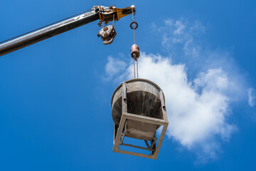 Bucket cement tank on crane hook blue sky background and lifting high construction site, Concrete Mix