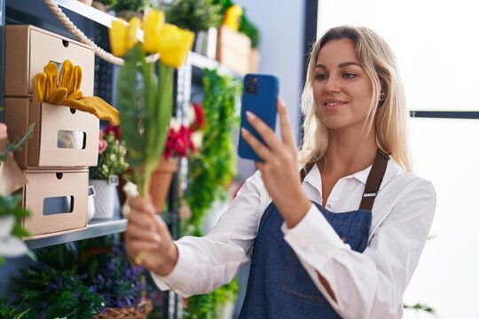 Young blonde woman florist make photo to flowers by smartphone at florist