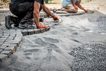 Construction workers installing and laying pavement stones on street, road or sidewalk. Worker...