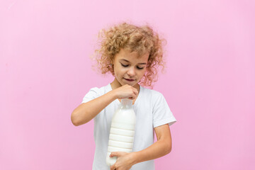 Little girl with a bottle of milk on a pink background