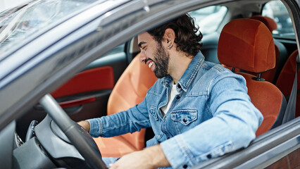 Young hispanic man smiling confident driving car at street