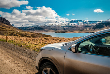 Traveling by car on the majestic landscapes in Iceland, snowy mountains and lake