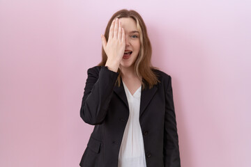 Fototapeta na wymiar Young caucasian business woman wearing black jacket covering one eye with hand, confident smile on face and surprise emotion.