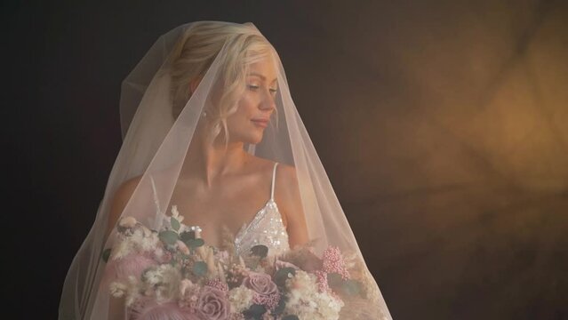 The bride in the studio under a veil under artificial lighting. Bride under artistic studio light. Beautiful girl under a veil, wedding day.