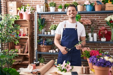 Young hispanic man florist cutting stem of flower at florist