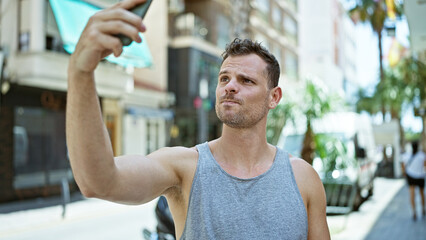 Handsome bearded man takes selfie on sunny urban street