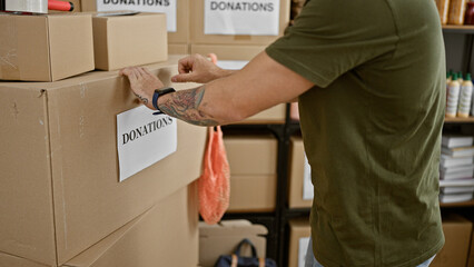A man in a warehouse organizes boxes labeled donations, implying volunteering or charity work. - obrazy, fototapety, plakaty