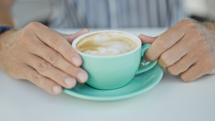 Close-up of adult hands holding a teal coffee cup at an outdoor setting, signaling a relaxing break.