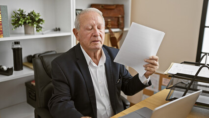 Mature business man working hard in heated office, making air with documents to beat the heat