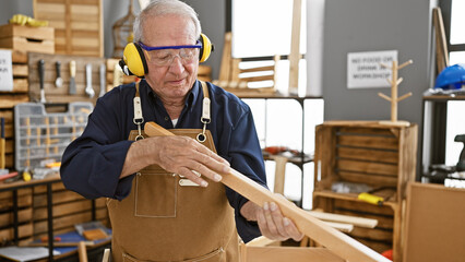 Resilient senior man, a seasoned carpenter, stands firm in his carpentry workshop, donning security...