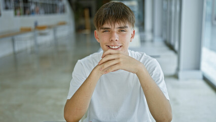 Smiling young caucasian male teen sitting at table in university library