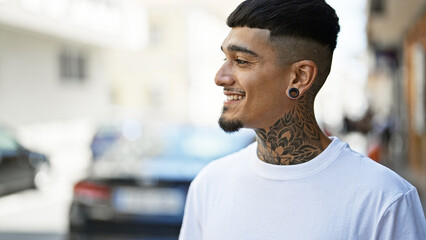 Confident and joyful young latin man, smiling and looking to the side on a bustling city street - obrazy, fototapety, plakaty