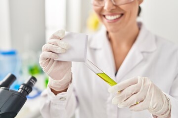 Young beautiful hispanic woman scientist holding test tube working at laboratory