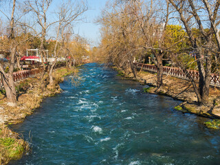 Fast flow of a clear mountain river in Turkey. Turquoise water, ripples on the water, waves, early spring, bare trees. Beautiful landscape