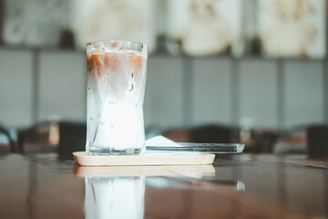 A glass of two layers iced mocha at nice coffee shop with beautiful blurred background of coffee with space for text