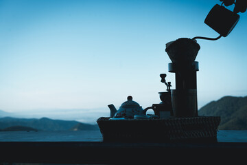 Image of a woman making drip coffee with a beautiful mountain and nature view in the background
