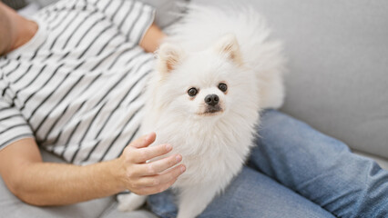 Young caucasian man with dog lying on sofa sleeping at home