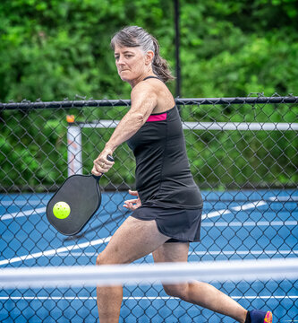 Athletic, female pickleball player with eye on the ball.