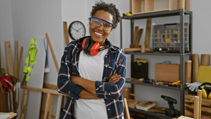 Confident woman with protective goggles stands in a carpentry workshop, embodying expertise and...