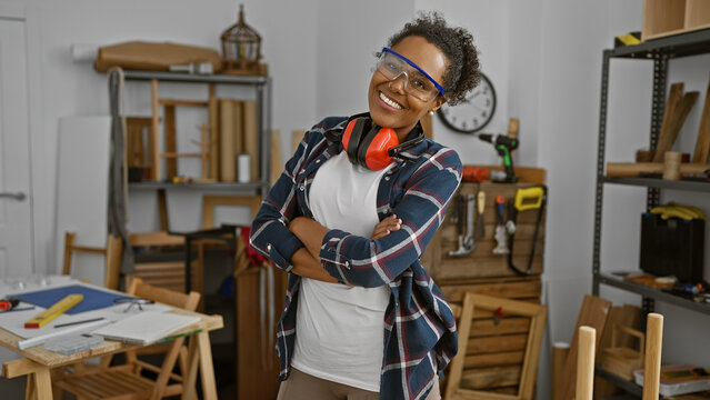 Confident woman with protective eyewear in a woodworking workshop, showcasing diversity in trades.