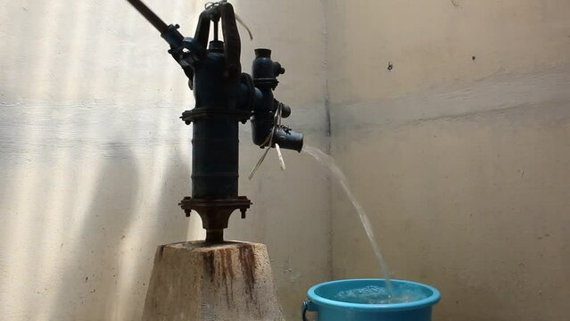 Traditional water pump with manual handle, with no electricity. Pump drain the water flow. No people. Selective focus