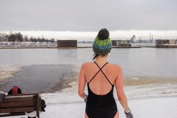 Brave woman winter swimming in icy lake, showcasing Nordic lifestyle and cold exposure wellness