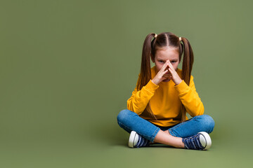 Full length photo of puzzled minded kid dressed yellow sweatshirt jeans sit think near empty space...