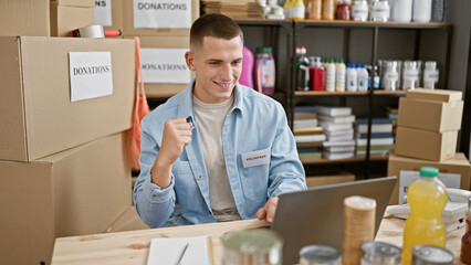 Handsome young man volunteering in a donation center, surrounded by cardboard boxes, working indoors.