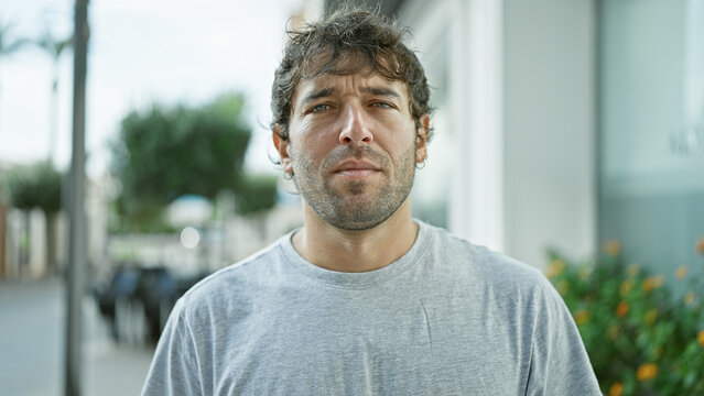 Confident young man with a serious expression, standing in an urban street setting, portraying a concentrated yet relaxed exterior