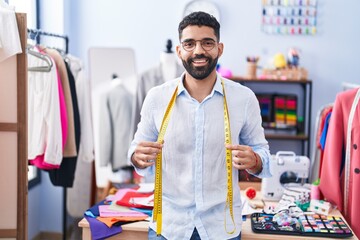 Young arab man tailor smiling confident standing at tailor shop