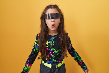 Adorable hispanic girl's shocked expression, wearing vr glasses, open-mouthed in disbelief and fear...
