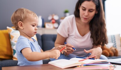 Mother and son sitting on sofa drawing on notebook at home